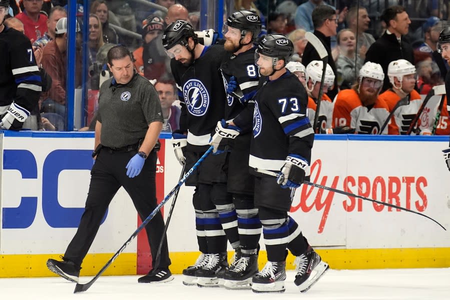 Tampa Bay Lightning defenseman Erik Cernak (81) is helped off the ice by left wing Conor Sheary (73) and left wing Nicholas Paul (20) after getting hurt blocking a shot by the Philadelphia Flyers during the second period of an NHL hockey game Saturday, March 9, 2024, in Tampa, Fla. (AP Photo/Chris O’Meara)
