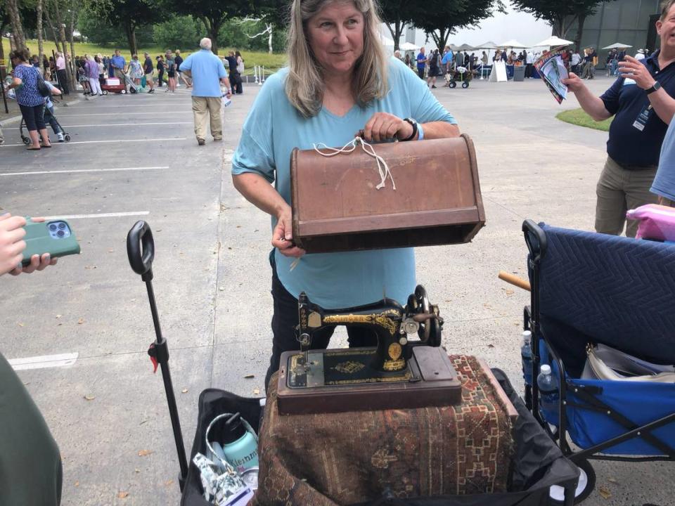 A visitor to the Raleigh, NC taping of “Antiques Roadshow” shows off a vintage sewing machine.