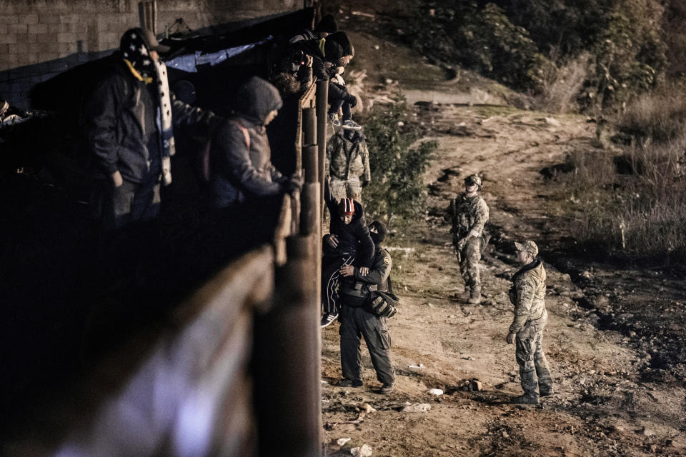 A U.S. Border Protection officer grabs a migrant as he goes down the border fence to get into the U.S. side to San Diego, Calif., from Tijuana, Mexico, Tuesday, Jan. 1, 2019. Discouraged by the long wait to apply for asylum through official ports of entry, many migrants from recent caravans are choosing to cross the U.S. border wall and hand themselves in to border patrol agents. (AP Photo/Daniel Ochoa de Olza)