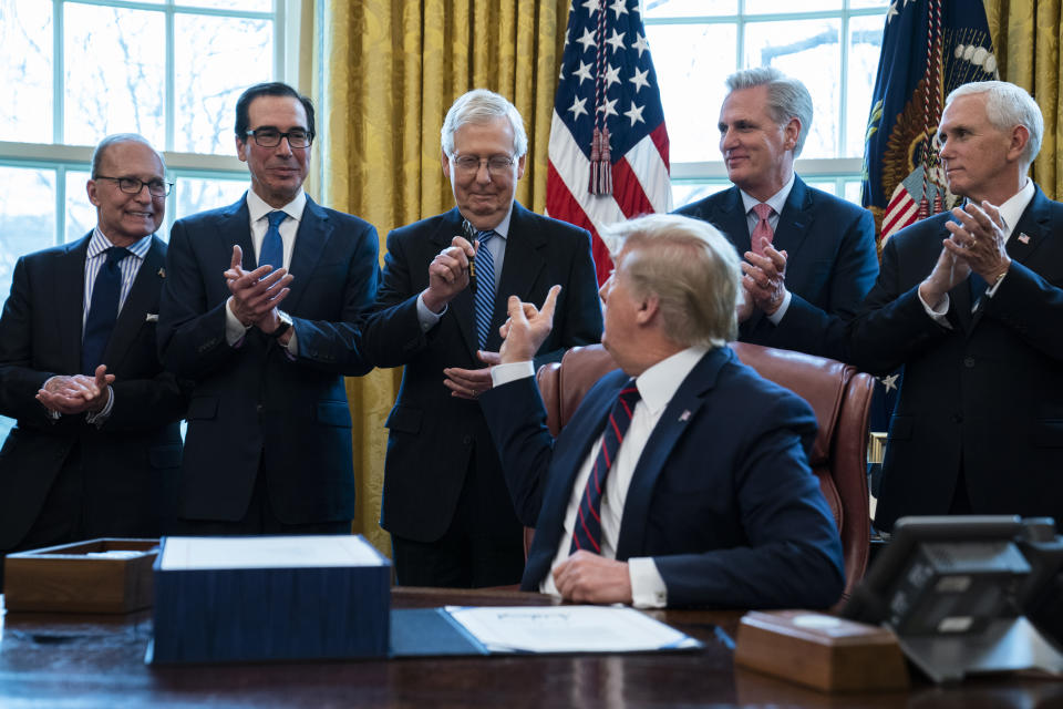 President Donald Trump hands a pen to Senate Majority Leader Mitch McConnell of Ky., after signing the coronavirus stimulus relief package in the Oval Office at the White House, Friday, March 27, 2020, in Washington. From left, White House chief economic adviser Larry Kudlow, Treasury Secretary Steven Mnuchin, McConnell, Trump, House Minority Leader Kevin McCarty, R-Calif., and Vice President Mike Pence. (AP Photo/Evan Vucci)