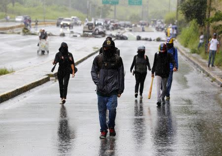 Manifestantes caminan bajo la lluvia en Caracas, donde se produjeron fuertes enfrentamientos en el día de una polémica elección de Asamblea Constituyente. Julio 30, 2017. REUTERS/Christian Veron