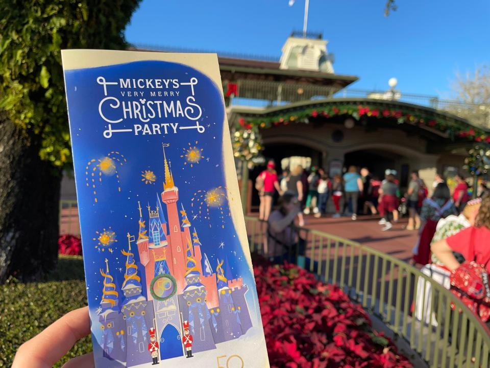 hand holding brochure for the mickey's very merry christmas party at magic kingdom