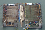 Workers try to raise the sunken Sewol ferry between two barges during the salvage operation in waters off Jindo, South Korea, Thursday, March 23, 2017. The 6,800-ton South Korean ferry emerged from the water on Thursday, nearly three years after it capsized and sank into violent seas off the country's southwestern coast, an emotional moment for the country that continues to search for closure to one of its deadliest disasters ever. (Choi Young-su/Yonhap via AP)