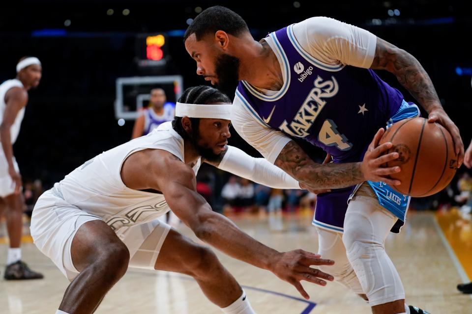 Oklahoma City Thunder guard Zavier Simpson, left, defends against Los Angeles Lakers guard D.J. Augustin (4) during the first half of an NBA basketball game in Los Angeles, Friday, April 8, 2022. (AP Photo/Ashley Landis)