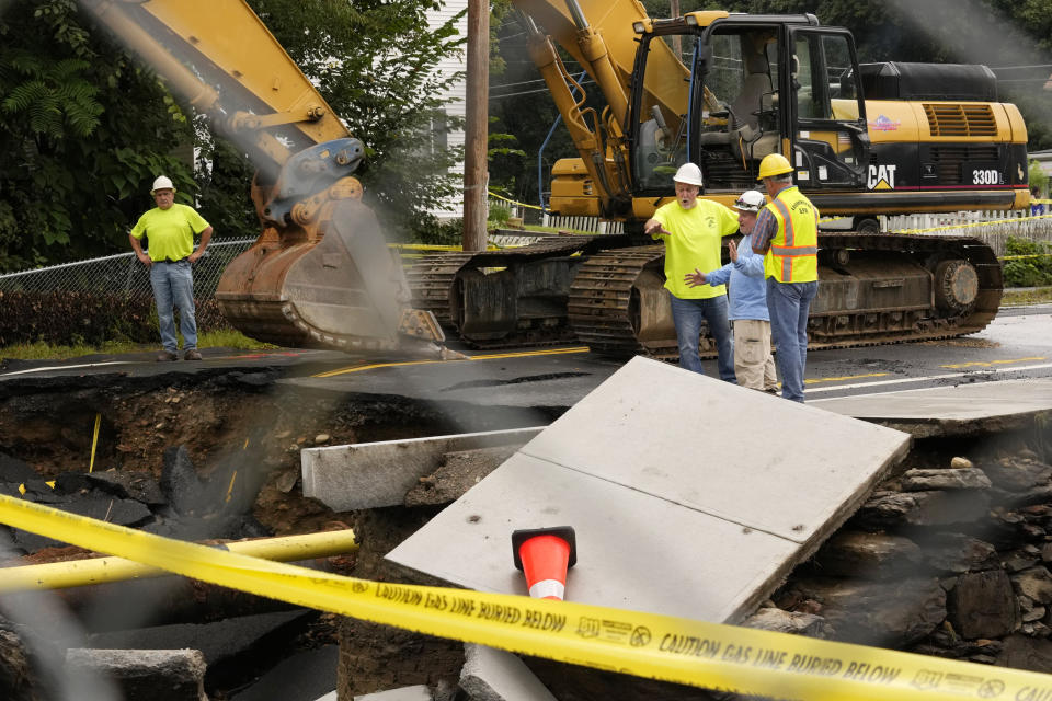 Public works officials examine the damage to a road that was washed away by recent flooding, Wednesday, Sept. 13, 2023, in Leominster, Mass. (AP Photo/Robert F. Bukaty)