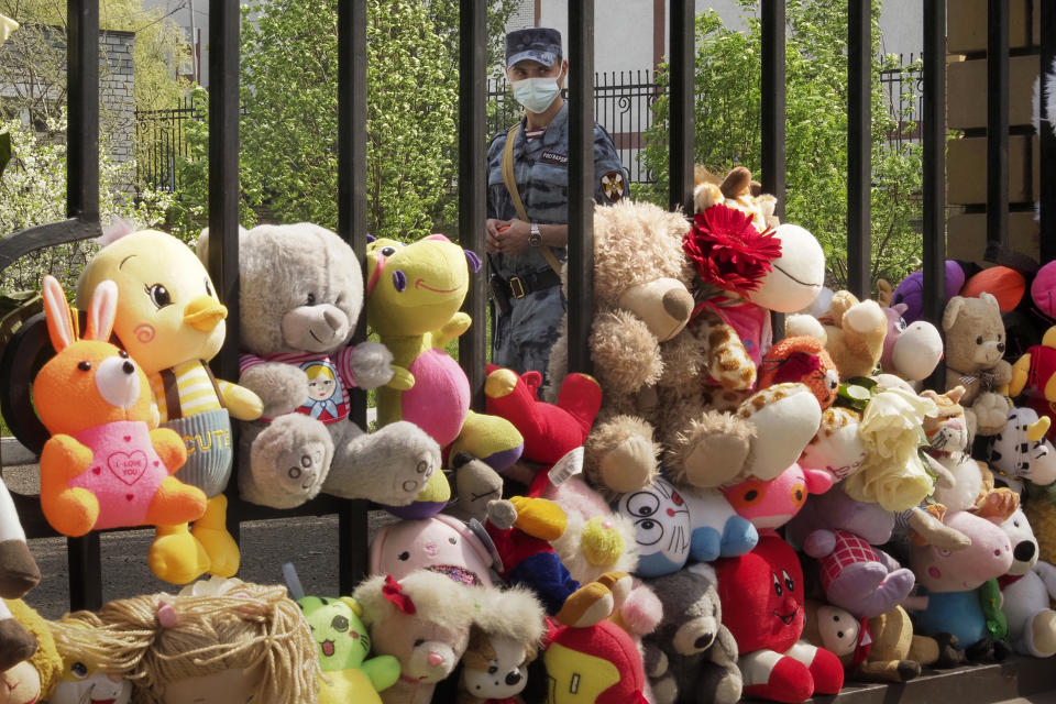 A Russian Rosguardia (National Guard) soldier stands guard at a school after a shooting on Tuesday in Kazan, Russia, Thursday, May 13, 2021, with toys brought by people in the foreground. Russian officials say a gunman attacked a school in the city of Kazan and Russian officials say several people have been killed. Officials said the dead in Tuesday's shooting include students, a teacher and a school worker. Authorities also say over 20 others have been hospitalised with wounds. (AP Photo/Dmitri Lovetsky)