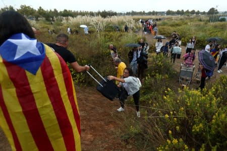 Passengers try to reach the airport as the road was blocked during a protest after a verdict in a trial over a banned independence referendum, in Barcelona