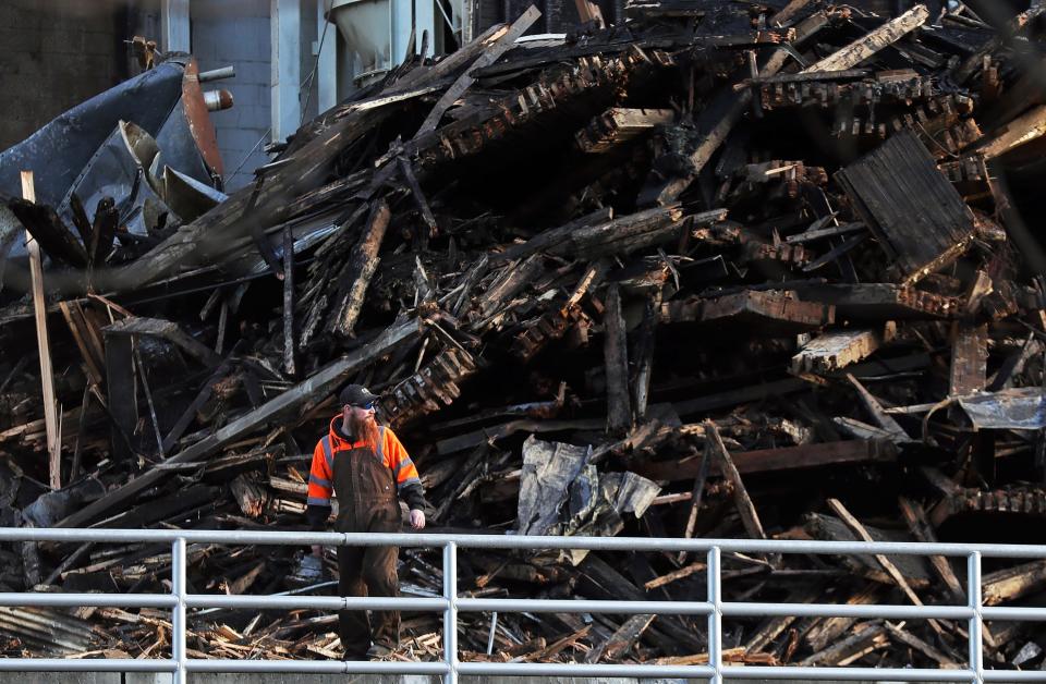 A worker navigates the rubble of the former Star of the West Milling Co. complex on Monday after last week's large structure fire.