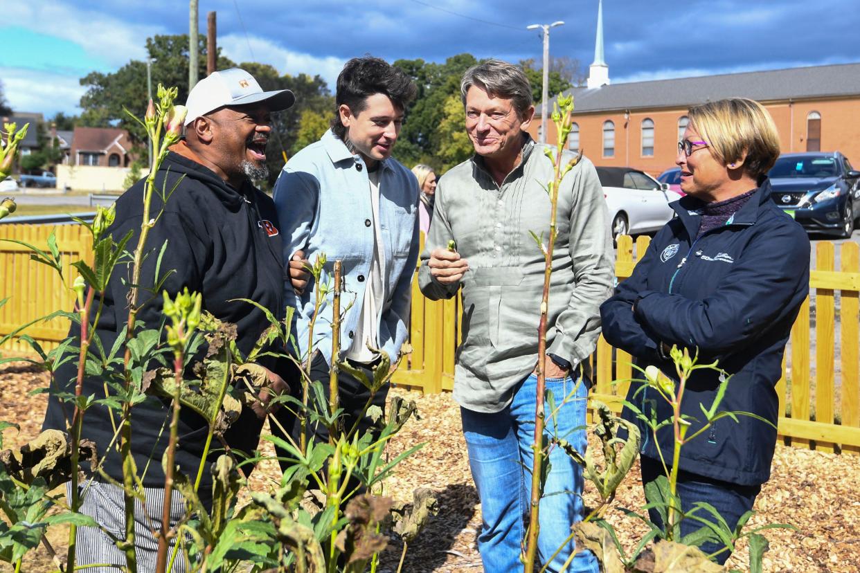 Chris Battle chats with Harrison, Randy and Jenny Boyd as the family tastes the okra grown at the Payne Avenue Missionary Baptist Church Community Garden on Oct. 15.