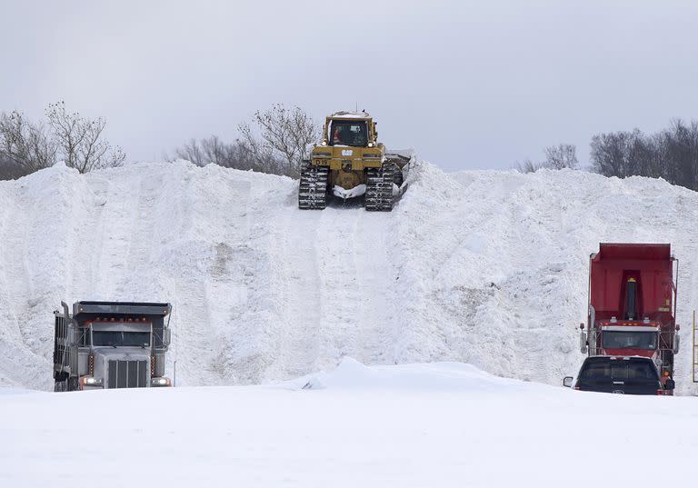 Las cuadrillas de trabajadores transportan la nieve en el estacionamiento del Erie Community College en Orchard Park, N.Y., el domingo 20 de noviembre de 2022.