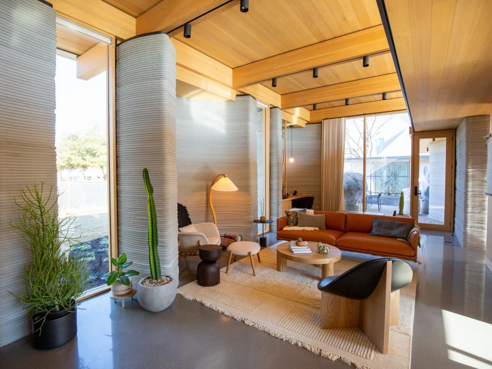 Inside Icon's over 2,000-square-foot House Zero in Austin. There's a lounge chair with a floor lamp surrounded by other furniture like a couch, coffee table, and another lounge chair.