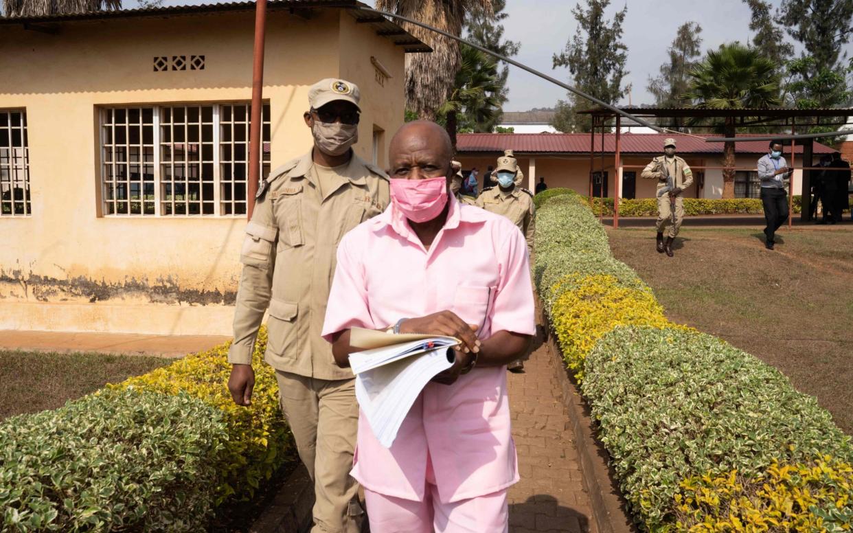 Paul Rusesabagina (R) in the pink inmate's uniform arrives from the Nyarugenge prison at the Nyarugenge Court of Justice in Kigali - SIMON WOHLFAHRT /AFP