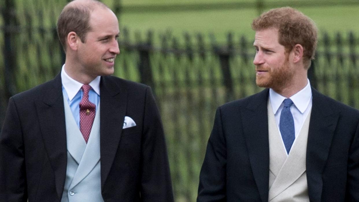 Prince Harry and Prince William looking at each other in morning suits