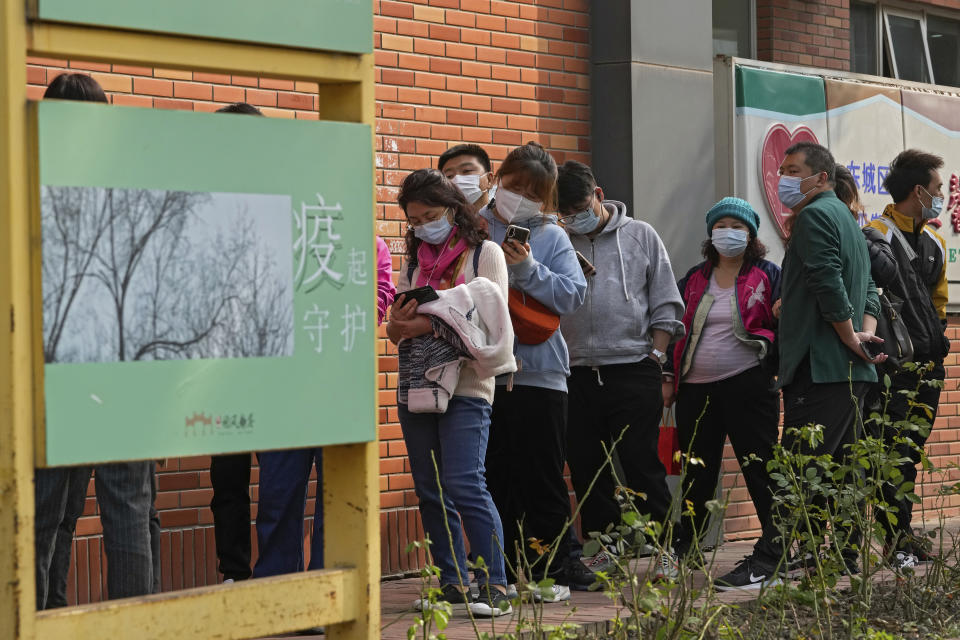 Residents wearing face masks to help curb the spread of the coronavirus line up to receive booster shots against COVID-19 at a vaccination site displaying a poster baring the words: "Epidemic protection" in Beijing, Monday, Oct. 25, 2021. A northwestern Chinese province heavily dependent on tourism closed all tourist sites Monday after finding new COVID-19 cases. (AP Photo/Andy Wong)