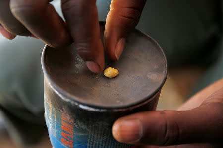 An artisanal gold miner picks up a gold nugget at an unlicensed mine in Gaoua, Burkina Faso, February 13, 2018. REUTERS/Luc Gnago