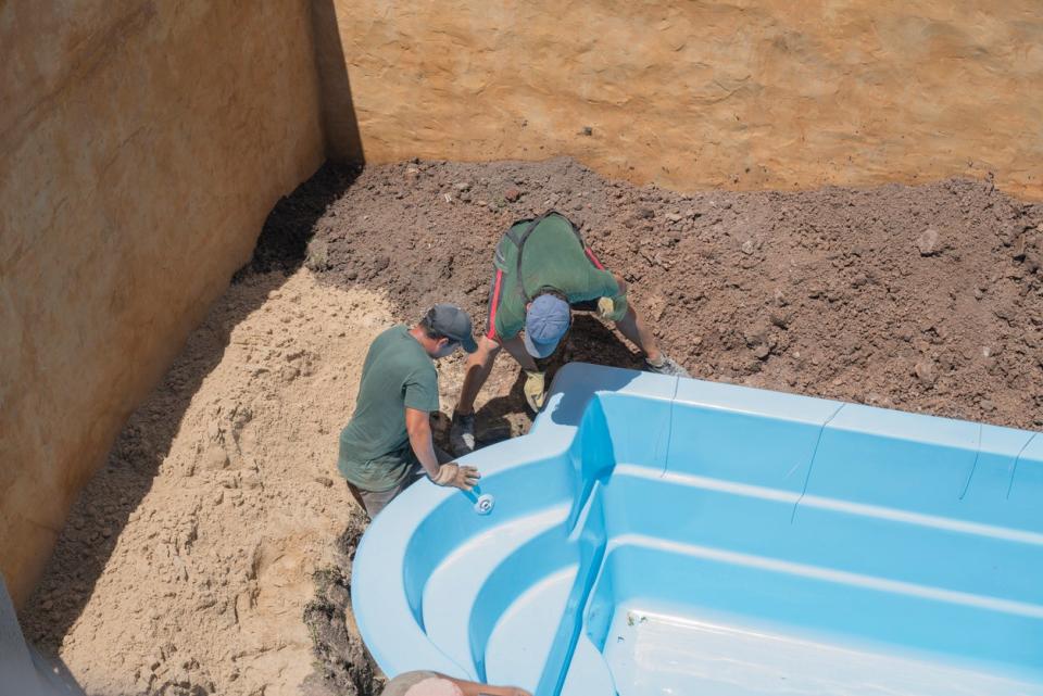 Two workers are in the process of building a pool.