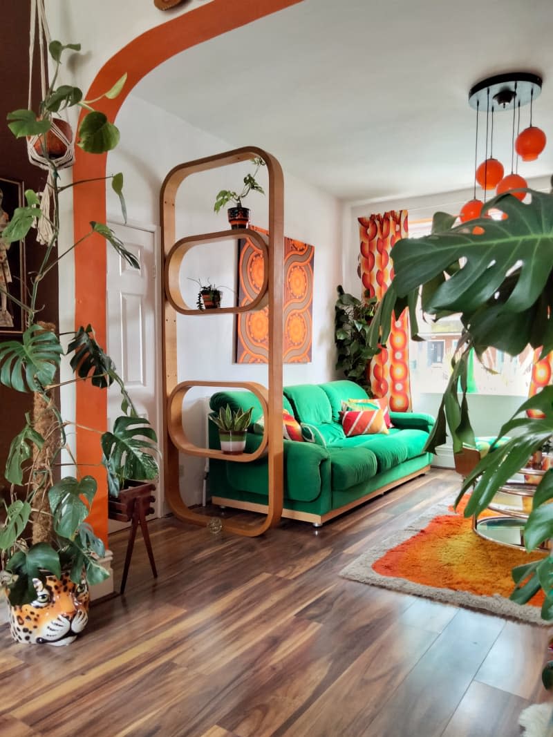 Colorful decorated living room with orange accents and green fabric couch.