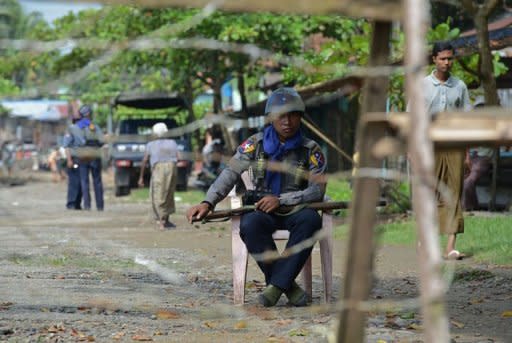 A policeman sits behind a barbed wire fence blocking the entrance into the Aung Mingalar quarter, turned into a ghetto after violence wracked the city of Sittwe, capital of Myanmar's western Rakhine state