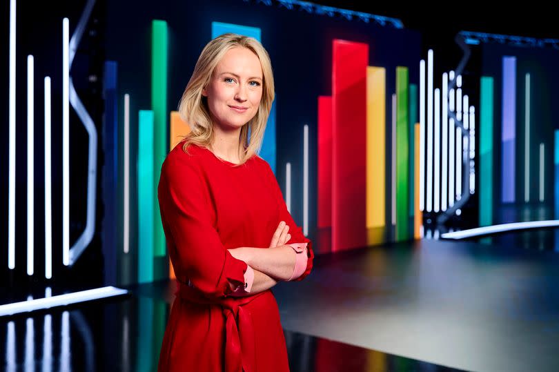 Sophie Ridge on set at Sky News standing up in a red dress