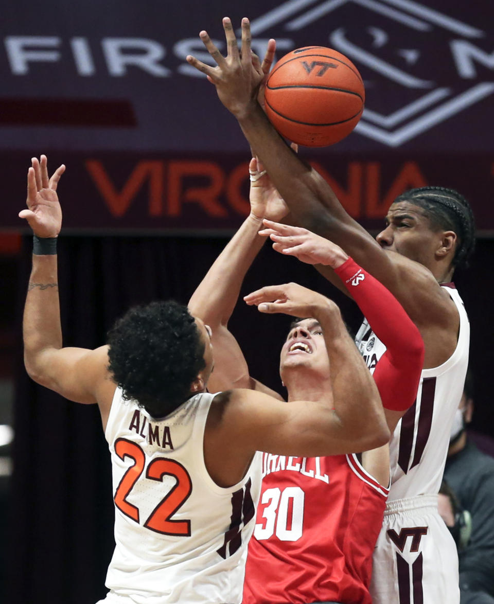 Cornell's Chris Manon (30) center, loses the ball while defended by Virginia Tech's Keve Aluma (22) and David N'Guessan during the first half of an NCAA college basketball game Wednesday, Dec. 8 2021, in Blacksburg, Va. (Matt Gentry/The Roanoke Times via AP)