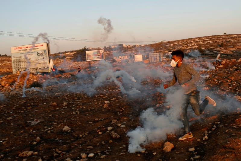 Palestinian demonstrator runs aways from tear gas fired by Israeli forces during an anti-Israel protest near the Jewish settlement of Beit El in the Israeli-occupied West Bank