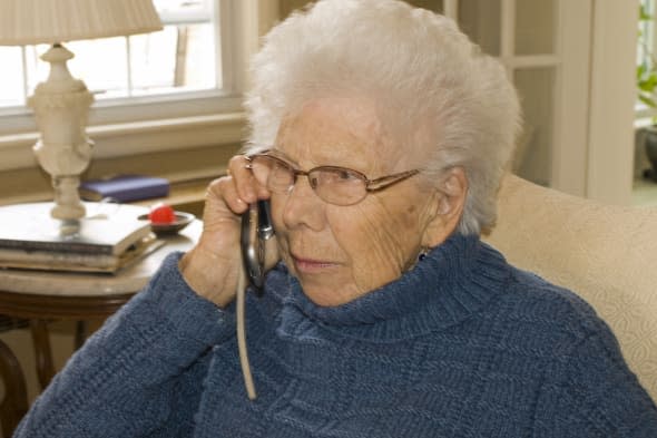 An elderly woman talks on a cell phone.