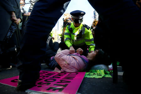 A police officer tries to move protester lying in the road outside the Houses of Parliament during a demonstration against fracking, in London, Britain, October 31, 2018. REUTERS/Henry Nicholls