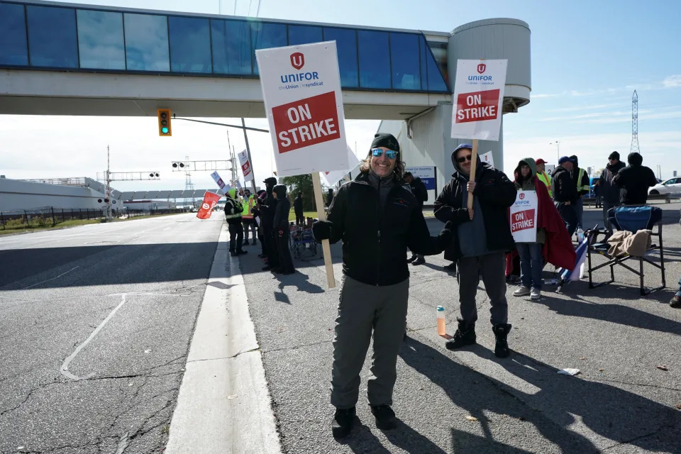 Unifor worker Claude Robitaille holds a sign at a picket line outside an entrance to the GM's Oshawa assembly complex, where the company’s profitable Chevrolet Silverado trucks are built, after 4,300 unionized workers went on strike at three General Motors plants, including Oshawa, Ontario, Canada October 10, 2023.  REUTERS/Arlyn McAdorey