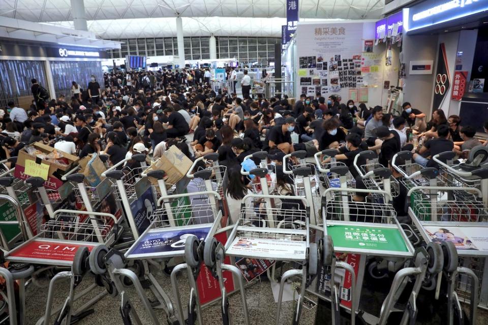 Protesters use luggage trolleys to block the walkway to the departure gates during a demonstration at the Airport in Hong Kong, Tuesday, Aug. 13, 2019. (AP Photo/Vincent Yu)