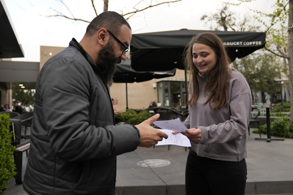 Verena al-Amil, 25, the youngest candidate running in the upcoming parliamentary elections, distributes campaign fliers, in Broumana, east of Beirut, Lebanon, April 8, 2022. The nationwide vote on May 15 is the first since Lebanon's economy took a nosedive and an August 2020 explosion at Beirut's port killed more than 200 and destroyed parts of the capital. Lebanon's various disasters have fueled anger at Lebanon's political elite, but few see any hope that elections will dislodge them. (AP Photo/Hussein Malla)