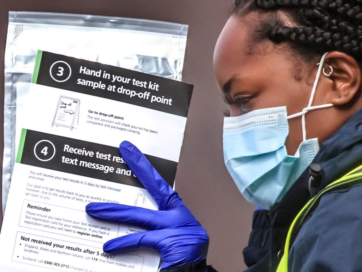 Staff hand out self test kits at a Coronavirus testing centre at the Last Drop Village Hotel in Bolton (PA)