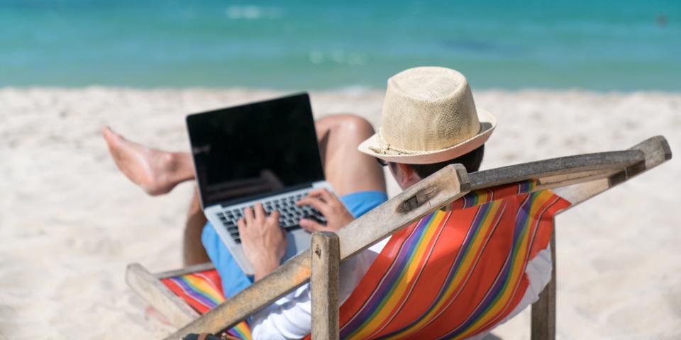 A person on a laptop at the beach