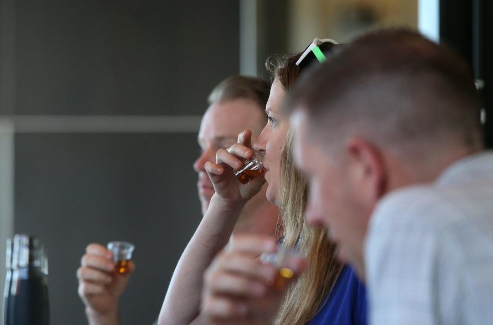 Maggie Menderski, center, Chris L’Heureux, right, and Mike Day take drinks of bourbon at the end of the tour of New Riff Distillery in Newport, Kentucky.June 30, 2022