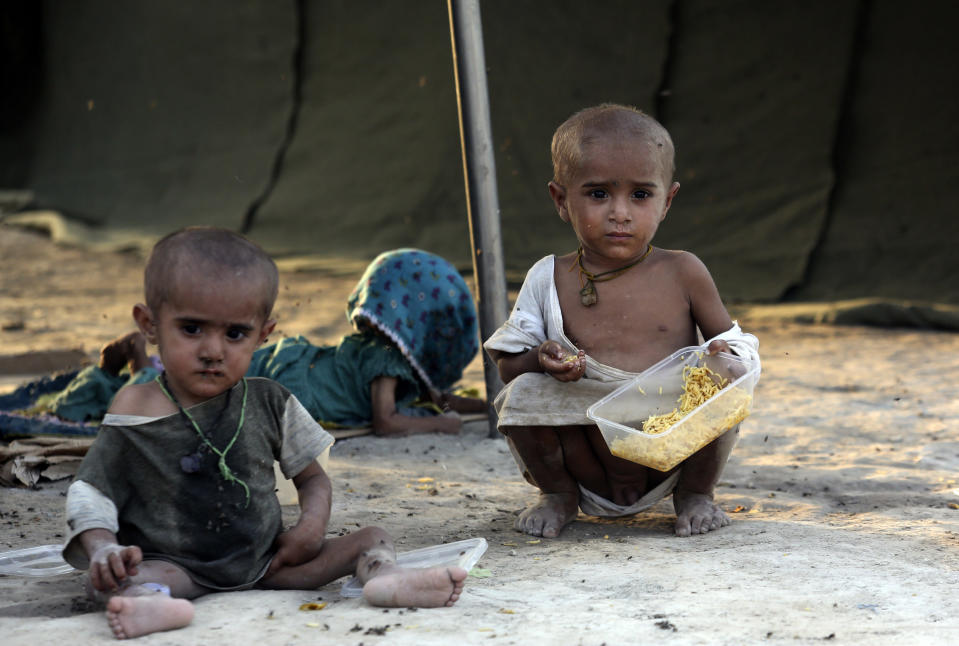 Children displaced by flooding from monsoon rains eat food at a temporary tent housing camp for flood victims and organized by the China government, in Sukkur, Pakistan, Wednesday, Sept. 7, 2022. (AP Photo/Fareed Khan)