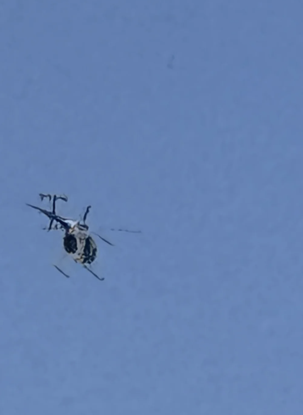 A helicopter flies in mid-air against a clear sky