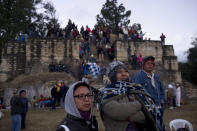 People watch in a ceremony at the Iximche archeological site to mark the end of the 13th Oxlajuj B'aktun in Tecpan, Guatemala, as the sun rises on Friday, Dec. 21, 2012. The end of the 13th Oxlajuj B'aktun marks a new period in the Mayan calendar, an event only comparable in recent times with the new millennium in 2000. While the Mayan calendar cycle has prompted a wave of doomsday speculation across the globe, few in the Mayan heartland believe the world will end on Friday. (AP Photo/Moises Castillo)