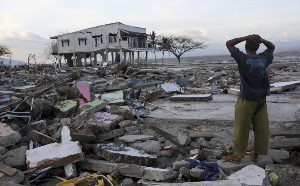 In this Saturday, Oct. 6, 2018, file photo, a villager stands amidst destruction caused by an earthquake and tsunami in Palu, Central Sulawesi, Indonesia. (AP Photo/Tatan Syuflana, File)