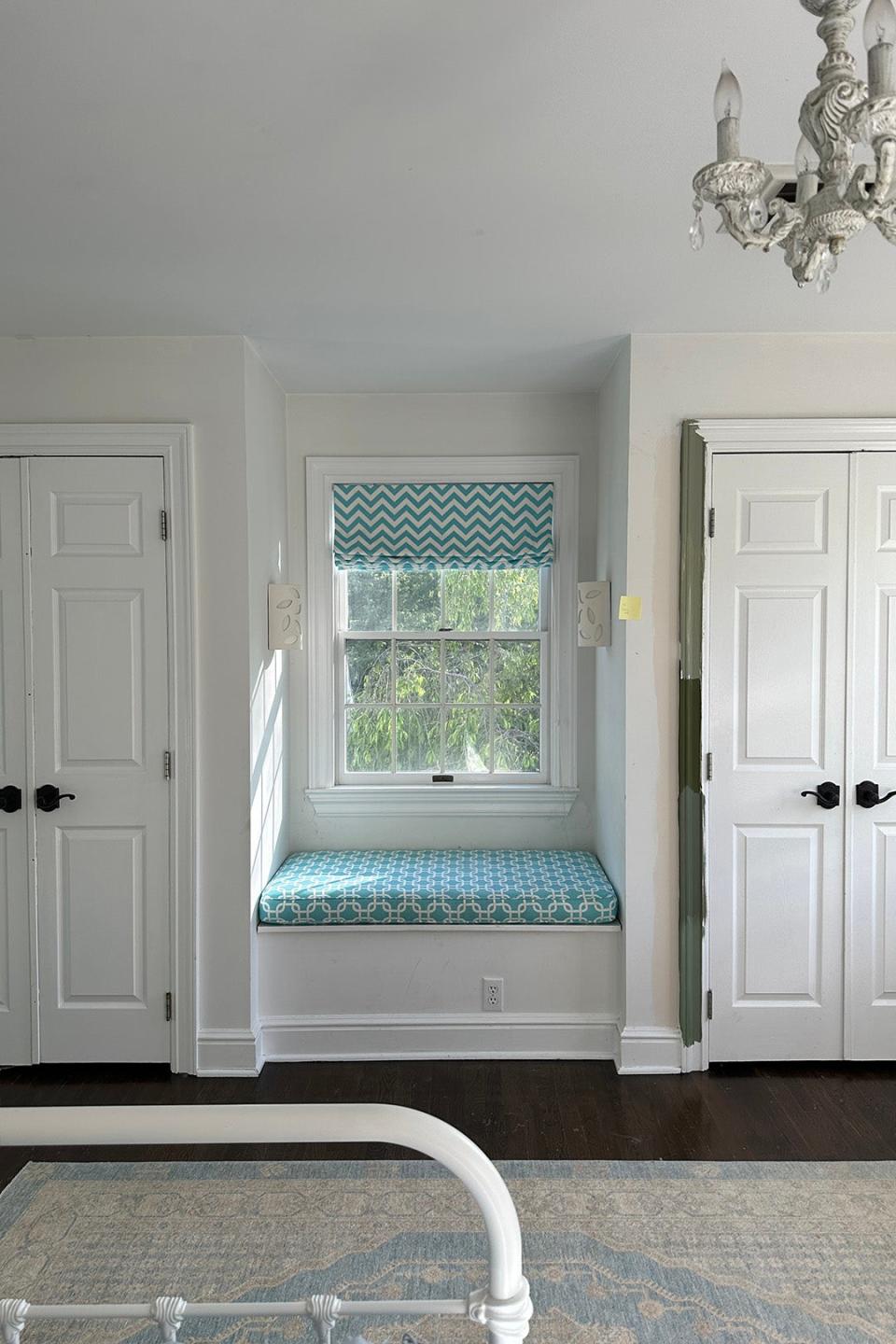 All-white room with two doors bookending a window.