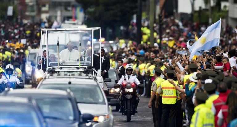 Pope Francis waves as he travels on the popemobile along the streets of Quito on July 5, 2015