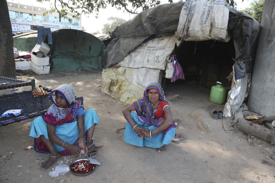 Indian residents of a slum near Sardar Patel Gujarat Stadium sit in front of their hut in Ahmedabad, India, Tuesday, Feb. 18, 2020. Authorities on Monday served eviction notices to 45 families living in the slum area ahead of the visit of U.S. President Donald Trump. Trump is visiting the city of Ahmedabad in Gujarat during a two-day trip to India next week to attend an event called “Namaste Trump,” which translates to “Greetings, Trump,” at a cricket stadium along the lines of a “Howdy Modi” rally he hosted for Indian Prime Minister Narendra Modi in Houston last September.(AP Photo/Ajit Solanki)