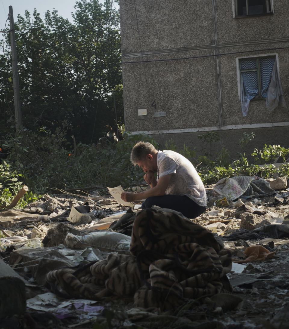 A local resident collects photos of his family left under the rubble after Russian shelling in Mykolaiv, Ukraine, Wednesday, June 29, 2022. (AP Photo/George Ivanchenko)