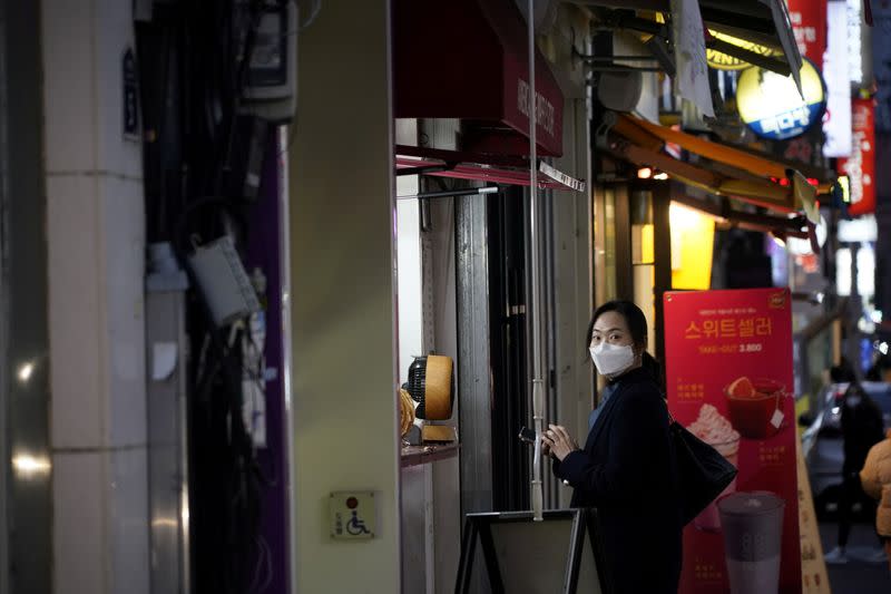 A woman wearing a mask to prevent contracting the coronavirus waits for her food at Dongseong-ro shopping street in central Daegu