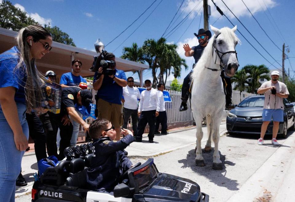 Franco Bernal, center, 6, battling childhood leukemia, waves to a City of Miami Police officer on a horse during his Wish Reveal on Thursday, July 18, 2024, with Make-A-Wish and City of Miami Police in Miami. Bernal loves the police and Disney World, and so they organized a parade to announce that his wish to go to Disney World is being granted next week.