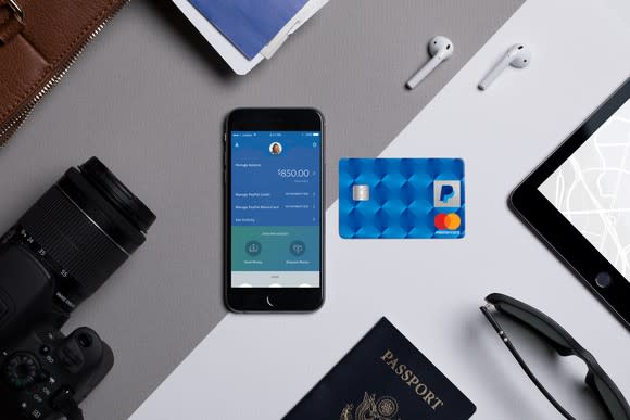 Smartphone with the PayPal app displayed and a PayPal branded credit card laying next to it.