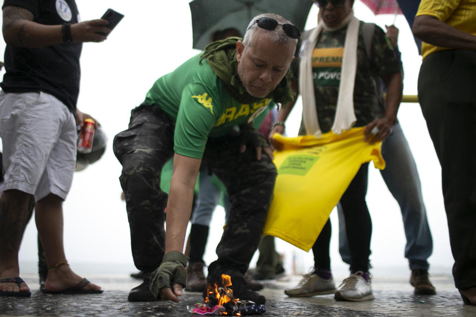 Supporters of Brazilian President Bolsonaro burn protective masks while rallying in favor of Bolsonaro's position that no one will be forced to use them and get an eventual coronavirus vaccine, on Copacabana beach in Rio de Janeiro, Brazil, Sunday, Nov. 1, 2020. Brazil has confirmed more than 159,000 deaths from the virus, the second highest in the world, behind only the U.S. (AP Photo/Bruna Prado)