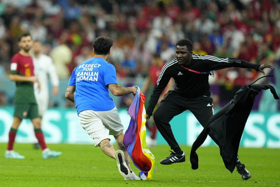 A pitch invader runs across the field with a rainbow flag during the World Cup group H soccer match between Portugal and Uruguay, at the Lusail Stadium in Lusail, Qatar, Monday, Nov. 28, 2022. (AP Photo/Petr David Josek)