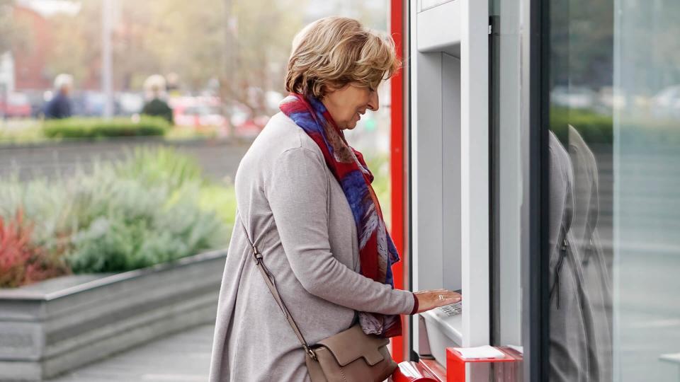 Senior woman using ATM in the city.
