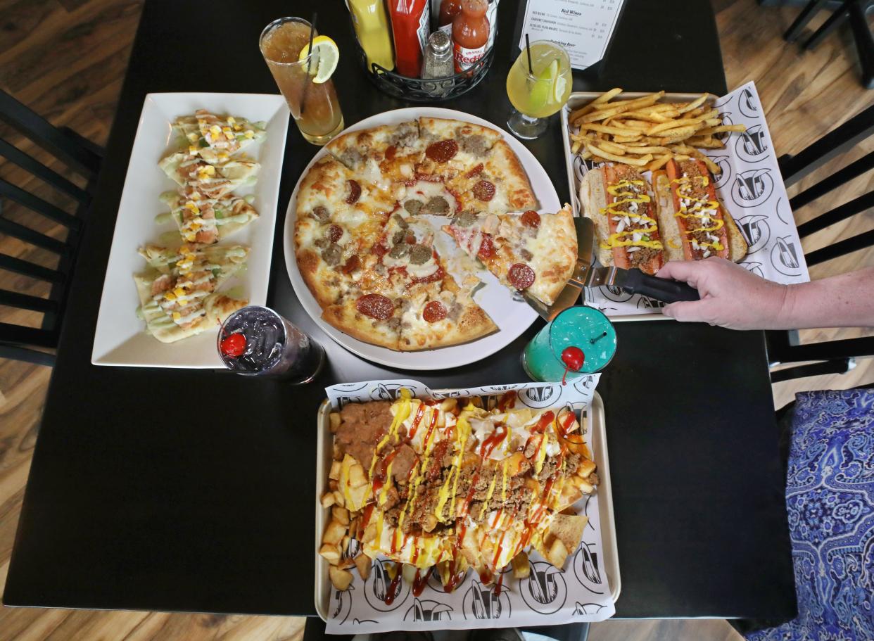 A table of delicious dining options at the newly opened Rabbit Hole Tavern in Rochester. Pictured clockwise from top center are 3 Ring Circus stone-fired pizza, Wayne's Franks, Rocchos and Seared Salmon Sushi Flatbread.