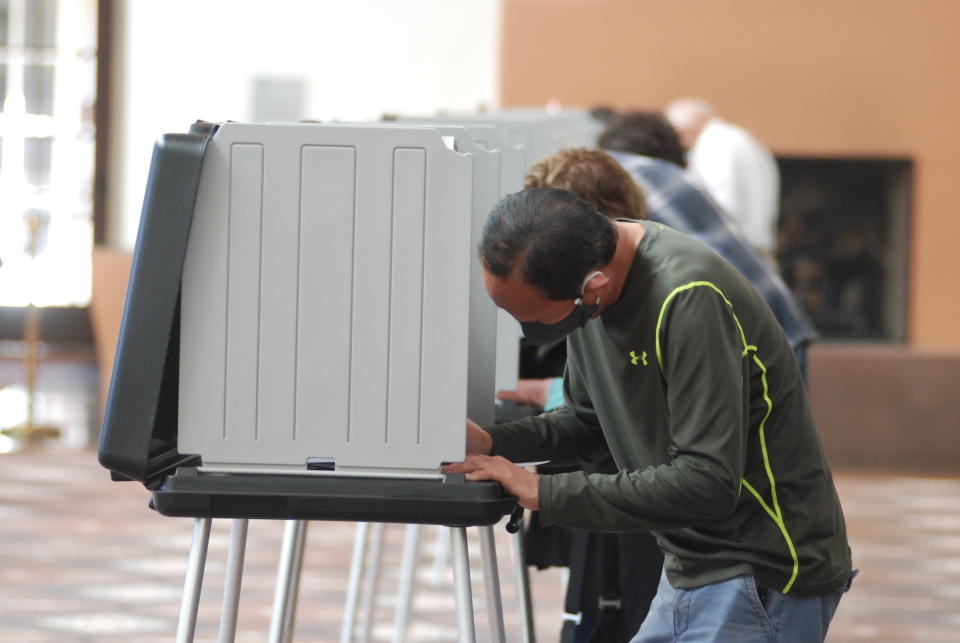 Will Halm, foreground, joins a steady stream of voters to participate in the first day of balloting in New Mexico, at the Santa Fe Convention Center on Tuesday, Oct. 6, 2020, in Santa Fe. Halm said he voted in-person and early to ensure his ballot counts and avoid crowds as a safety precaution against COVID-19. Election officials are witnessing a massive surge in absentee ballot requests. (AP Photo/Morgan Lee)