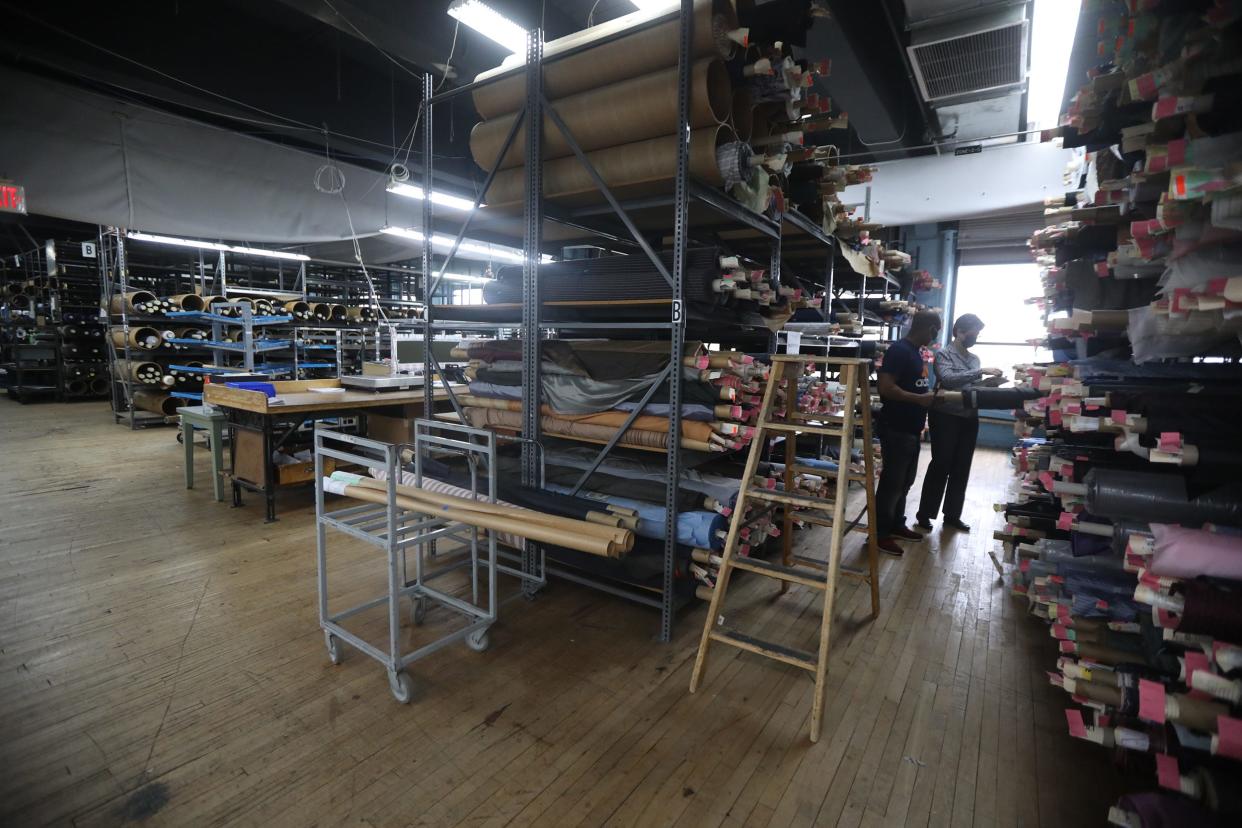 Employees at Hickey Freeman look over shelves of fabric and lining on April 13, 2021.